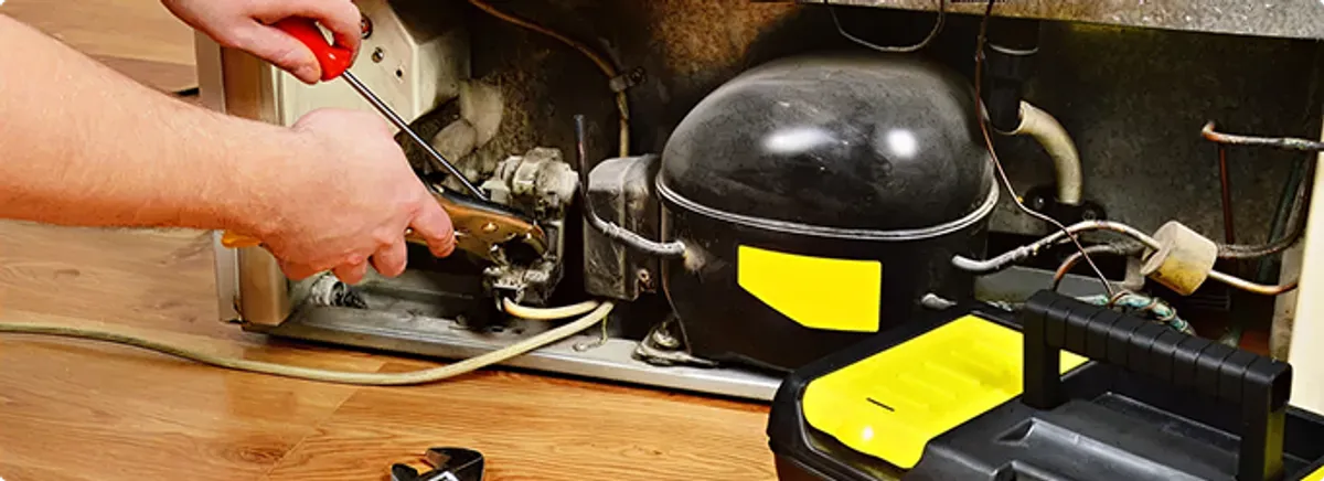 Refrigerator repair technician fixing the compressor and wiring in East Orange, NJ