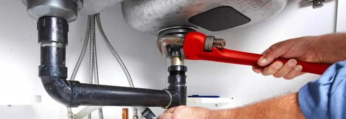 Garbage disposal repair technician tightening the sink drain and disposal connection in Newark, NJ