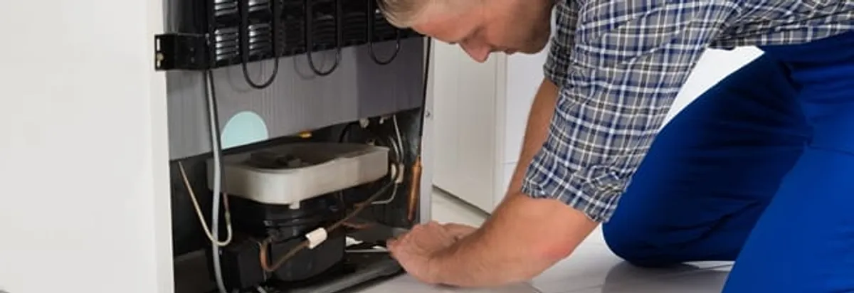 Refrigerator repair technician servicing the compressor and condenser area in Newark, NJ