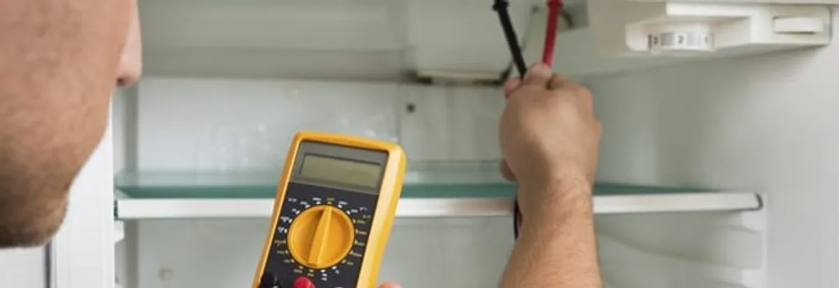 Refrigerator repair technician testing electrical components with a multimeter in Newark, NJ